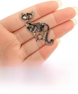 Detail of vintage bronze cat brooch with green crystals and textured metal finish
