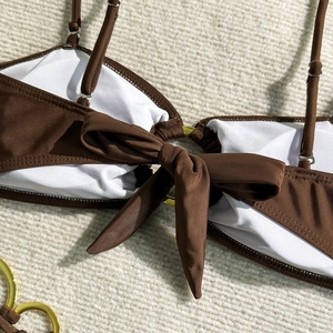 Détail du haut de bikini marron avec anneau doré et nœud papillon frontal