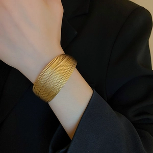 Primo piano di un bracciale a fascia multistrato placcato oro sul polso di una modella