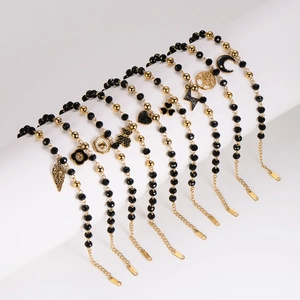 Chic black beaded bracelets with gold leaf, heart, and tree charms on a white stand