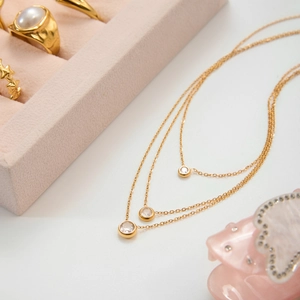 Close-up of triple-layered 18k gold-plated zircon pendant necklaces in a jewelry box