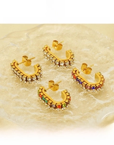 Detailed macro view of gold U-shaped earrings set with colorful zircon and titanium steel
