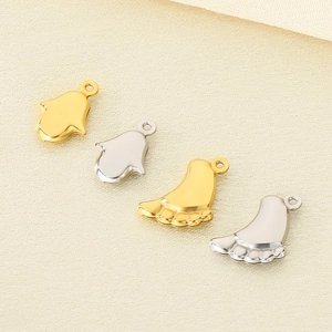 Golden and silver stainless steel Hamsa and baby feet charms on beige fabric
