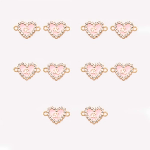 Detailed macro view of ten pink heart-shaped alloy pendants with R initial and rhinestones