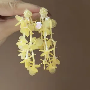 Detail of yellow flower tassel earrings with translucent beads and sequins