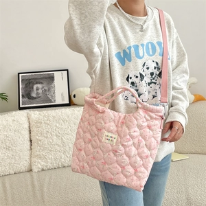 Sac bandoulière rose matelassé avec motifs lapin et fleurs porté par un mannequin
