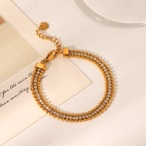Detail of gold double-row zircon chain bracelet with polished metallic finish