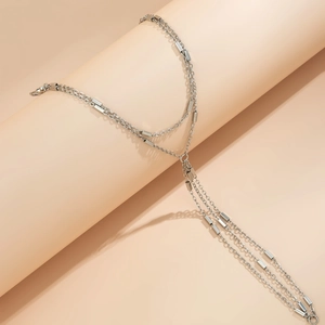Close-up of silver double-layer body chain with hanging tassels on a beige background