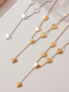Detail of layered gold and silver heart necklaces with matte brushed metal finish
