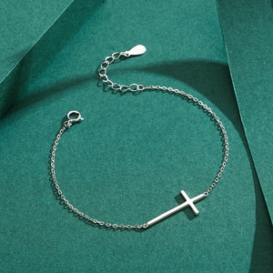 Minimalist S925 sterling silver cross bracelet with polished finish on a green background