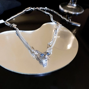Detailed close-up of a silver sphinx cat pendant with blue zircon eyes on a heart mirror