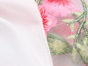 Détail macro de la broderie florale en maille et des coutures de qualité sur la robe