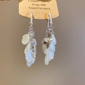 Détail de boucles d'oreilles à pompons argentés avec pétales de perles et cuivre