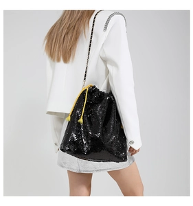 Detail of black sequined bucket bag with yellow drawstrings and golden chain strap