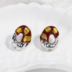 Detail of French vintage earrings with red enamel and irregular silver metal surfaces