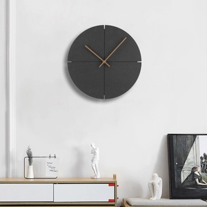 Minimalist dark gray wall clock with wooden hands on white wall above a wooden side cabinet