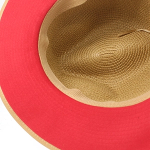 Detailed close-up of wide-brim fedora hat showing red brim and woven straw interior