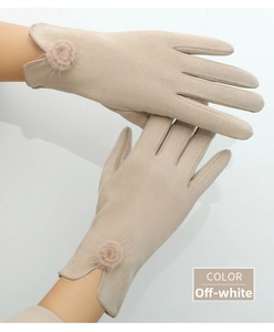 Detail of off-white thermal suede gloves featuring V-shaped cuffs and elegant fur pom-poms
