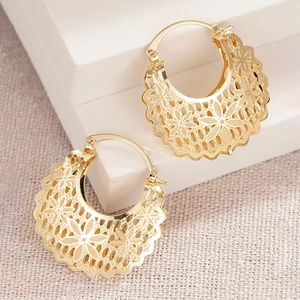 Macro detail of gold hoop earrings featuring intricate floral hollow-out pattern