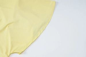 Detailed macro shot of double-needle stitching on the hem of a light yellow dress