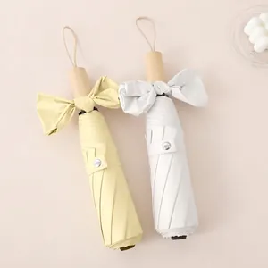 Three-fold sun umbrella with wooden handle and large bow tie decorative accents