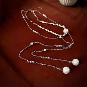 Elegant long tassel necklace with silver beads and pearls on dark red velvet