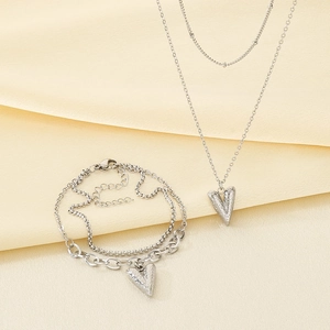 Detail view of silver heart pendant double-layer necklace and bracelet set on soft fabric