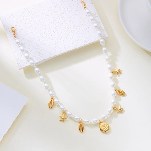 Detail of bohemian pearl necklace with gold starfish and shell pendants on white surface