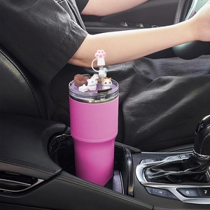 Detail of a pink 40oz tumbler lid with cat figurines and paw straw cover in car cup holder