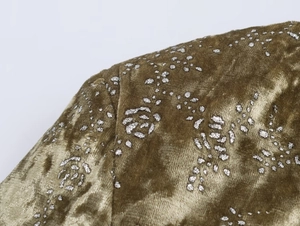 Macro view of olive velvet fabric with metallic floral print and detailed stitching