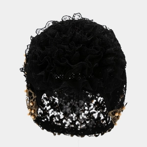 Détail du turban en dentelle florale noire avec bords à volants et perles dorées élégantes
