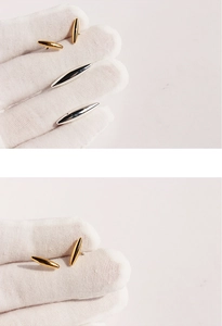 Detailed macro shot of gold and silver spindle stud earrings held with white gloves