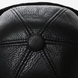 Close-up of black PU leather winter cap with stitch detail and top button design