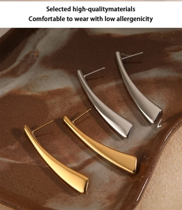 Detail of minimalist 316 stainless steel long curved earrings in gold and silver finishes