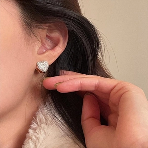 Close-up of heart-shaped zircon earrings in rose gold finish on model's ear