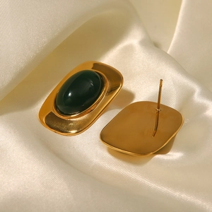 Boucles d'oreilles ovales dorées 18k avec pierre vert émeraude sur soie blanche lisse
