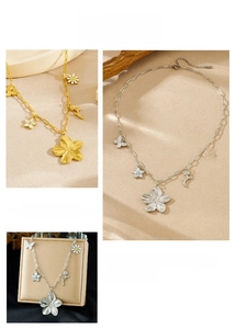 Detail of flower and butterfly charms on gold and silver stainless steel necklaces