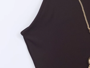 Macro view of gold chain detail on halter neck dress with high-quality dark fabric
