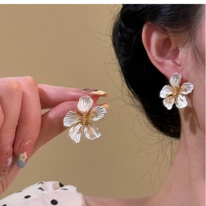 Detailed view of silver flower earrings with golden core on hand and ear