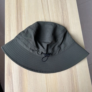 Close-up of a dark green nylon sun hat with an adjustable black drawstring buckle