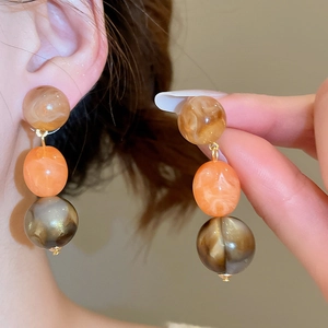 Macro detail of vintage acrylic resin earrings with amber and orange marble beads