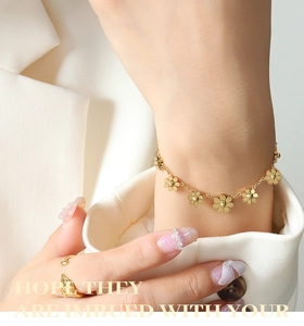 Dettaglio del bracciale a margherita placcato oro 18K indossato con un elegante abito bianco