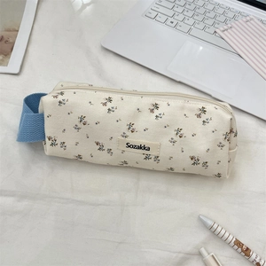 Detailed close-up of floral pencil case with navy handle on a desktop setting