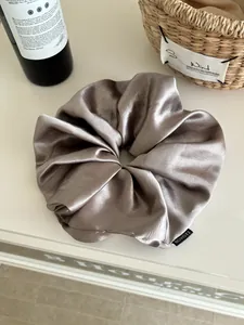 Detailed view of champagne satin scrunchie with fashion label on silk-like fabric