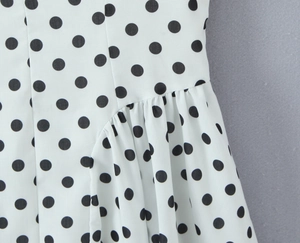 Détail du tissu en mousseline blanche à pois noirs avec des coutures plissées fines