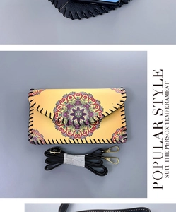 Close-up of yellow crossbody phone bag with mandala pattern and black whipstitch edging