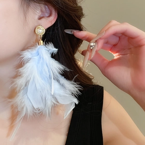 Macro shot of light blue feather earrings with pearl inlay and vintage gold base
