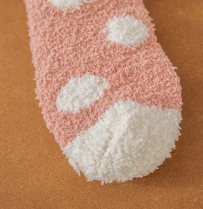 Close-up of soft pink coral fleece socks with white polka dots for winter warmth