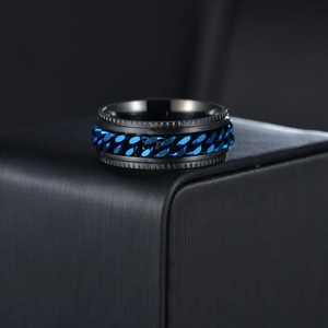 Close-up of black matte stainless steel spinner ring with blue chain inlay on dark stand