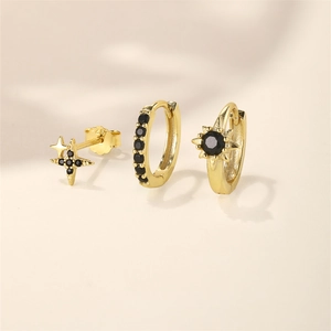 Macro shot of a three-piece gold earring set with black zircon stars and Gothic accents